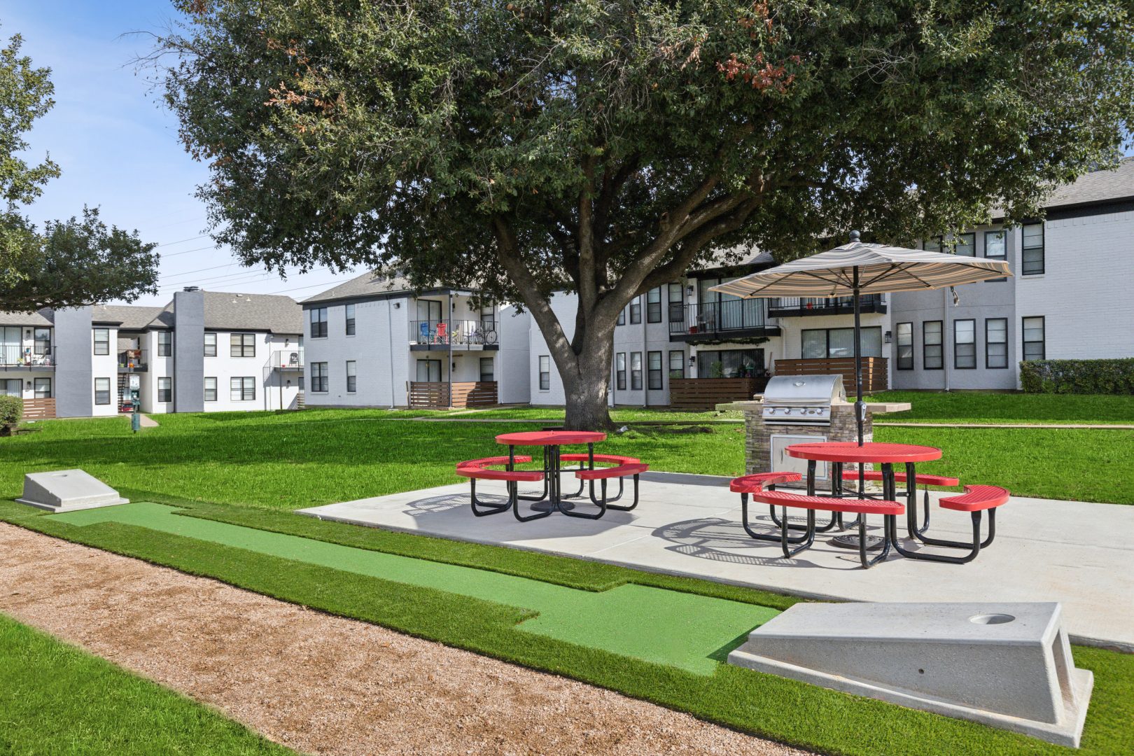a picnic table and benches in front of a large apartment complex at The Brookbend